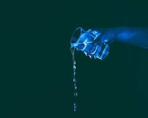 A person pouring a glass of water from a jug